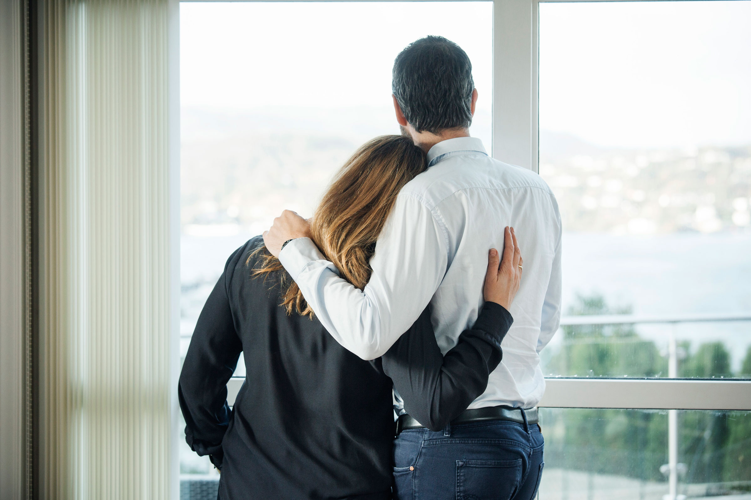 Par holder om hinanden og kigger ud af vindue, fotografi