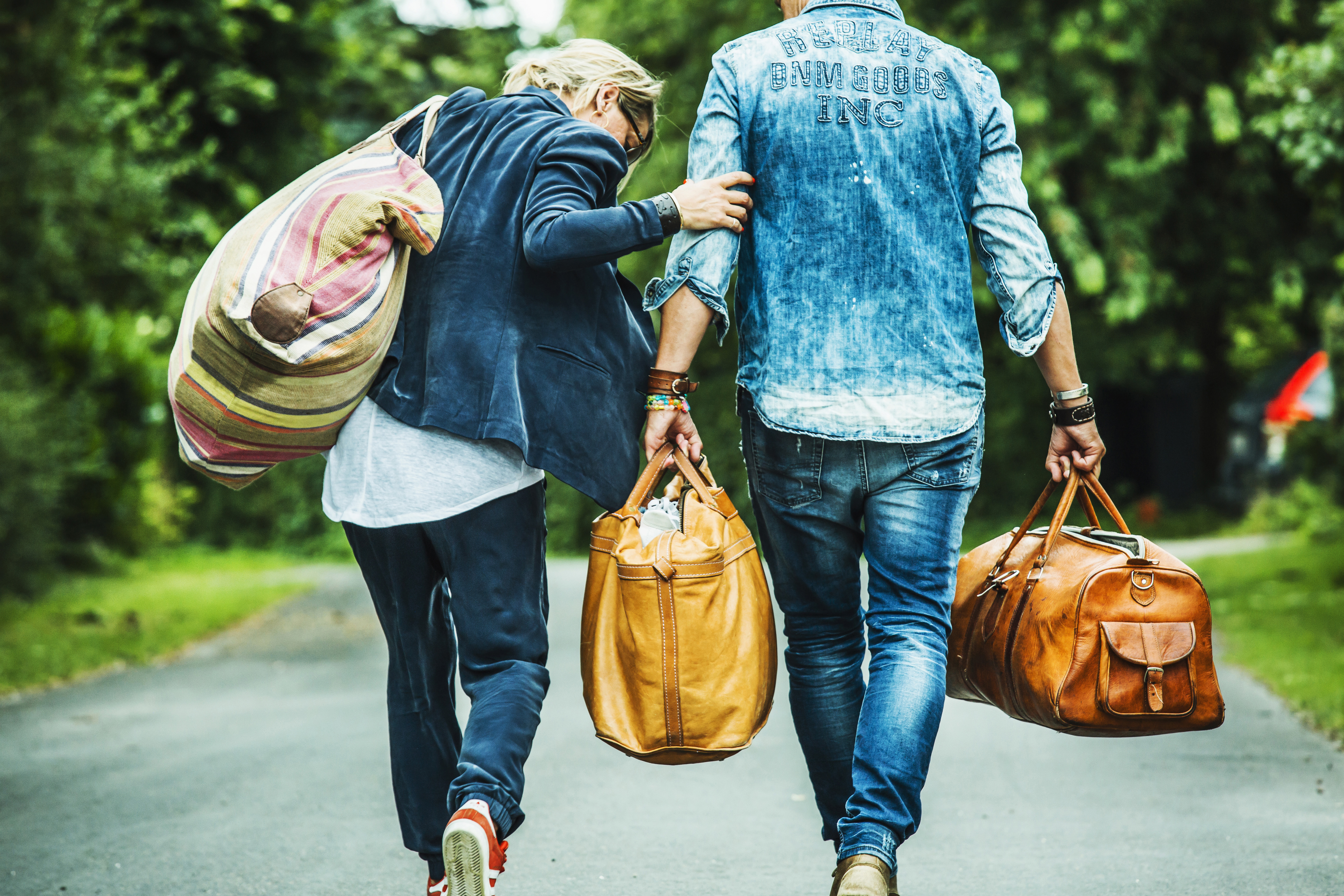 Par går på asfalteret vej med tasker, fotografi