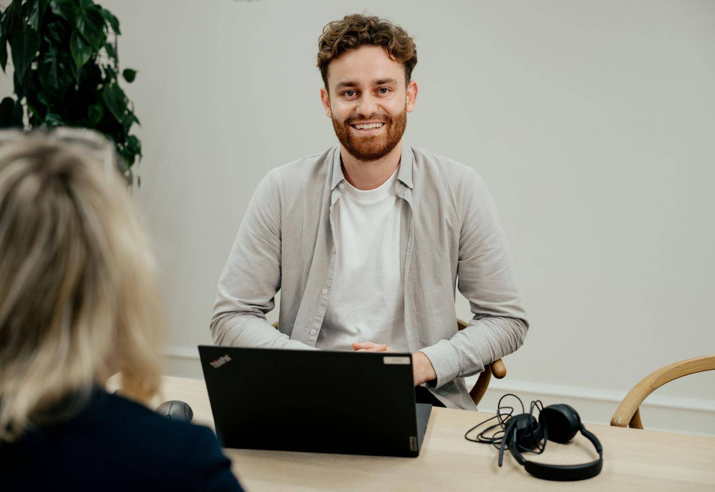 Voksen person med computer foran ved et bord over for en anden person