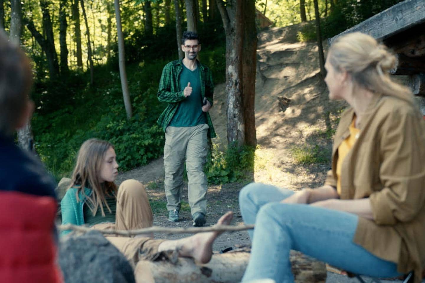 Mand går mod sin familie i skoven imens han giver en tommel op