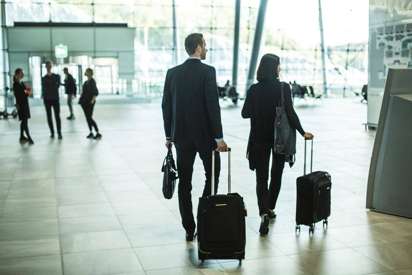 To personer går med kufferter i en lufthavn