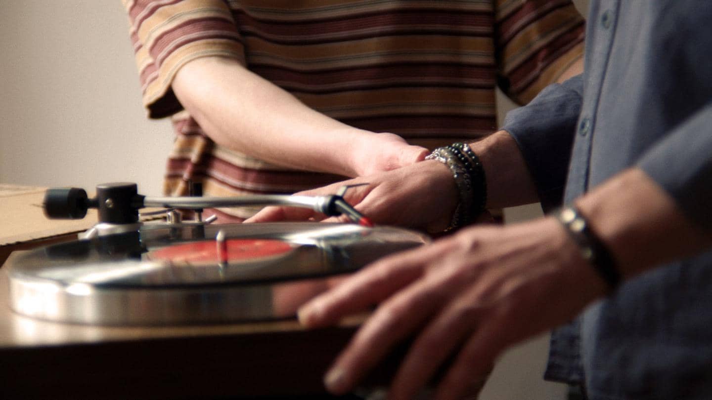 Hænder rører ved pladespiller med LP-plade på, fotografi