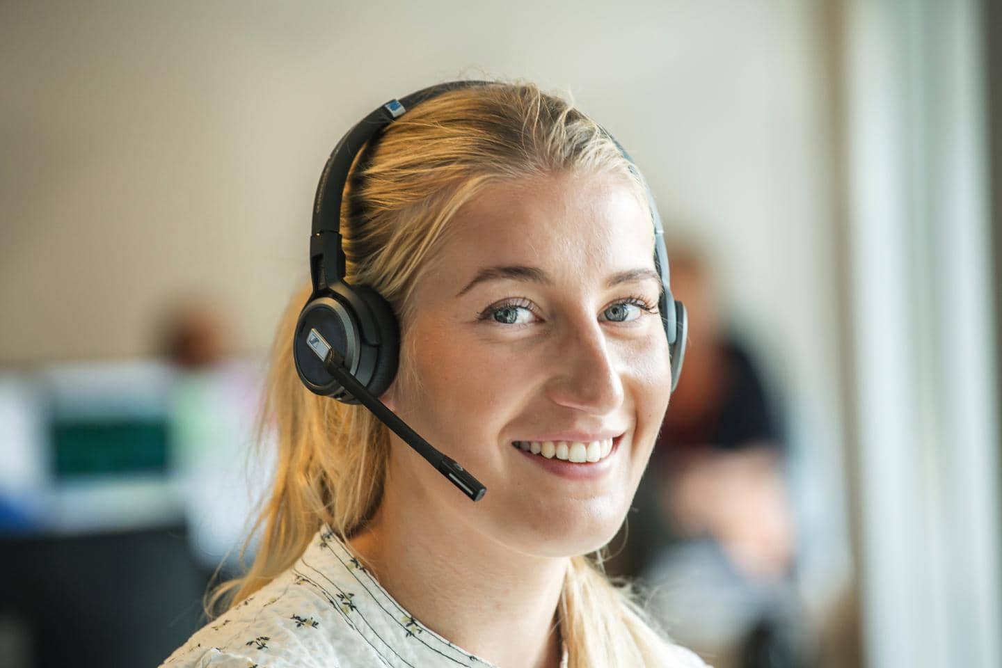Lyshåret kvinde med headset smiler, fotografi