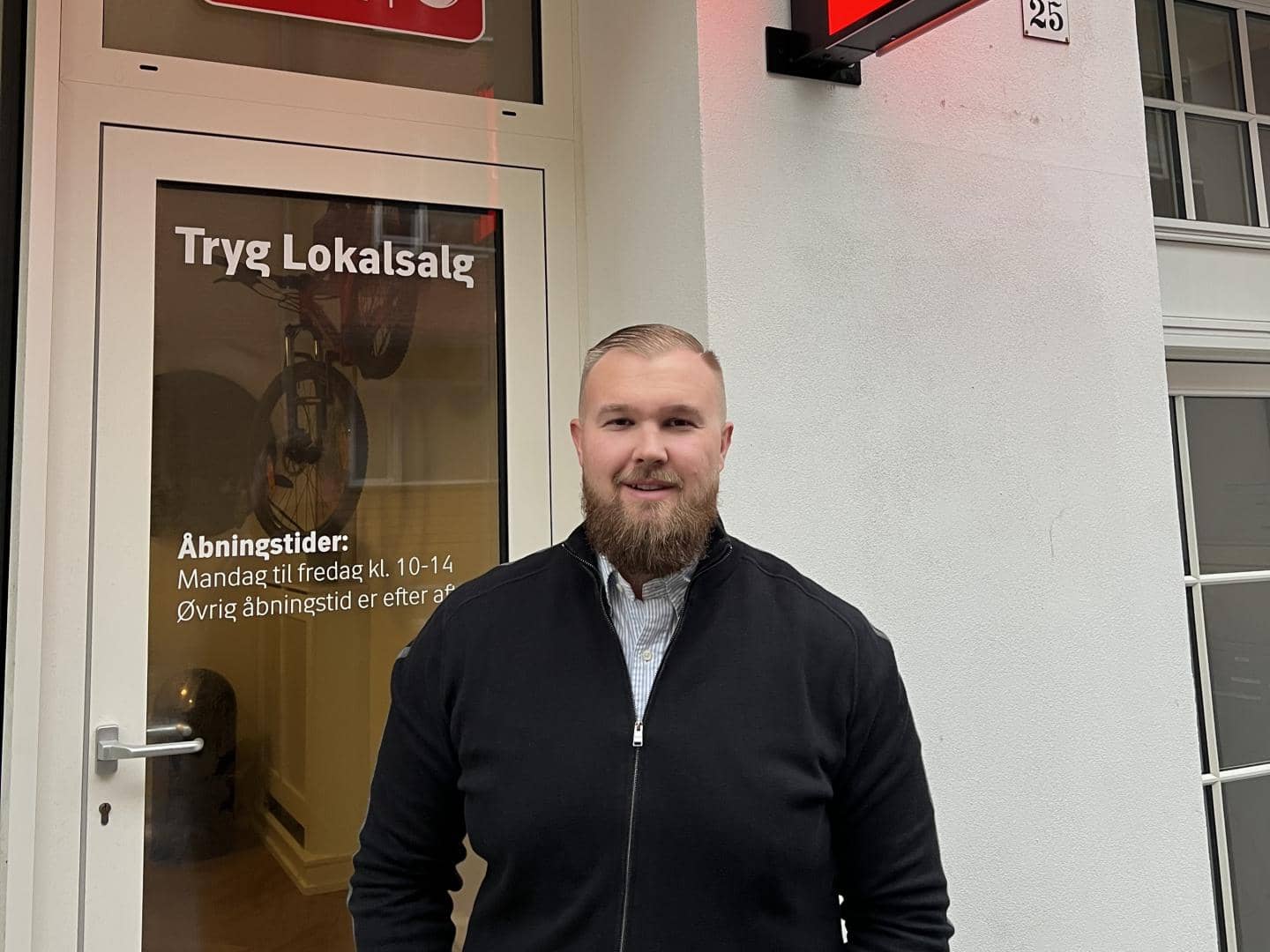 Mand står foran dør til butik