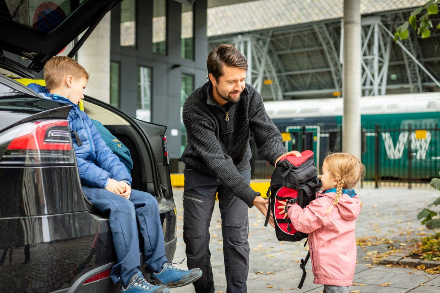 Far pakker tasker i bagagerummet med hjælp fra sine børn, fotografi